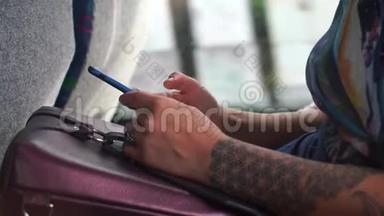 手臂上有纹身的女孩在公共<strong>交通工具</strong>中使用智能手机