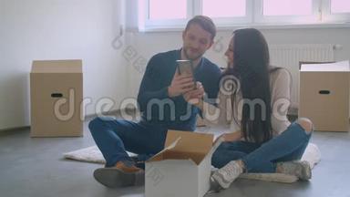 年轻的白种人夫妇坐在新房子的地板上，选择了<strong>相框照</strong>片的位置。