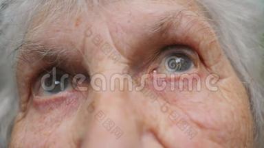 老妇人的眼睛从一边移动到另一边，然后看着镜头。 一位长着皱纹的老太太的眼睛