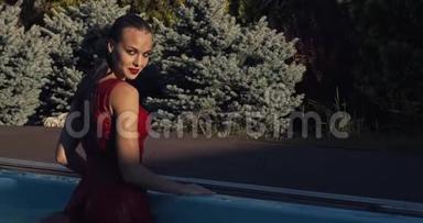 年轻女子穿着红色连衣裙从游泳池出来，微笑着摆姿势，4K