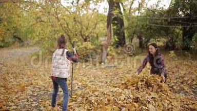 美丽的小女孩和她的母亲用<strong>耙子</strong>清理院子里的黄叶