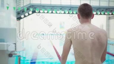 年轻的游泳运动员正准备在游泳池里游泳。 运动员在比赛前进行训练。 回头看看。 健康