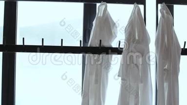 几个白色浴袍挂在衣架上，靠近一扇窗户，可以看到一个热气腾腾的贝森。