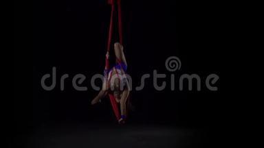 女空中体操运动员在<strong>黑</strong>色背景下表演红色<strong>丝绸</strong>。 精彩的杂技表演.. 慢动作。 144