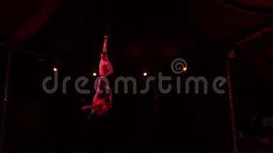 两个杂技演员在马戏团的穹顶下翱翔，在晚上跨着两个劈叉