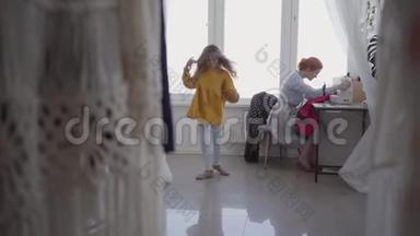 红发女人在灯光室的窗户附近的桌子旁<strong>缝衣服</strong>。 小女儿在旋转