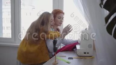 漂亮的红发女人坐在靠窗的桌子边缝衣服，教女儿如何做