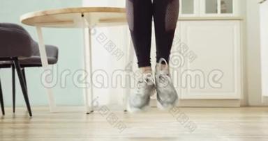 运动型女人的腿在厨房的家里跳绳做有氧运动训练。