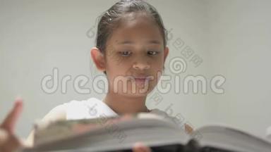 可爱的微笑的年轻女孩穿着白色衬衫在图书馆看书。 漂亮的女青少年喜欢搜索<strong>有用</strong>的<strong>信息</strong>。
