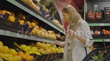 在杂货店手工挑选柠檬的妇女在超市的水果和蔬菜通道挑选柠檬。