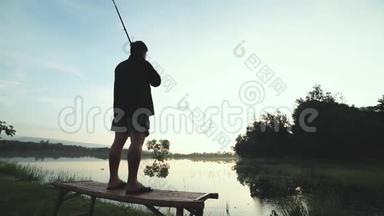 一个人拿着鱼竿独自站在湖边钓鱼的剪影