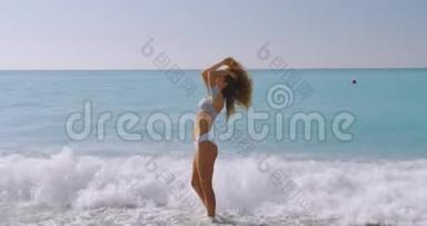 那个女人在美丽的海滩上无忧无虑。 女孩放松，在苗条的身体里表现出快乐和快乐，以减肥饮食