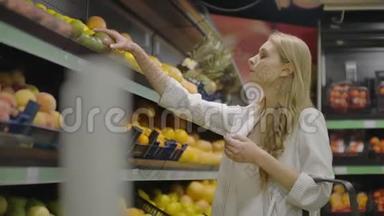 年轻的女人在杂货店里选择熟芒果。 纯素<strong>零废物</strong>女孩购买水果和有机织品