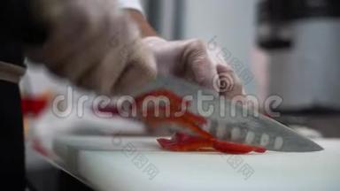 一名男子厨师在餐厅厨房用一把大<strong>餐刀</strong>切红胡椒。