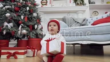 可爱的蹒跚学步的孩子穿着圣诞衣服，坐在地板上，在圣诞节的背景上送着漂亮的礼物