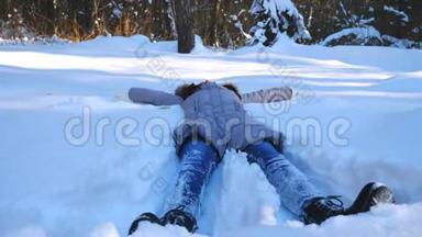 无法辨认的年轻女孩躺在雪地草地上做天使。 快乐的女人在雪地里玩，享受冬天的时光