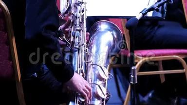 一个`爵士乐队中萨克斯管上穿黑色西装的男人。 后景。 特写镜头。 铜管乐队的音乐家。 节日