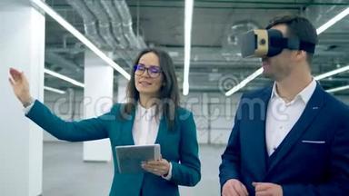 一个穿着VR眼镜的男人和一个房地产经纪人穿过大厅。 房地产经纪人与客户。