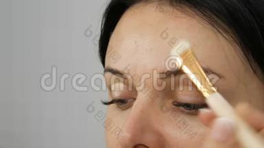 一种特殊的刷子在模特的眼皮上涂上<strong>粉底</strong>霜，然后再开始化妆眼睛和女人的脸