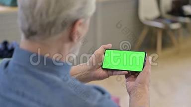 老人在绿色模拟屏幕智能手机上观看视频