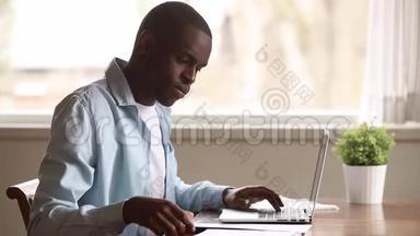 一个精力充沛、手提电脑文件的黑人坐在办公桌前