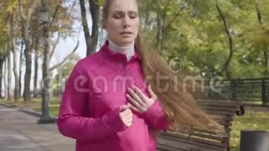 年轻的高加索女人穿着粉红色运动服，因为胸痛而在跑步过程中停下来。 女生跑步时感觉不好