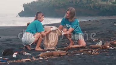 两名志愿者穿着蓝色t恤在海滩上<strong>清理垃圾</strong>，把<strong>垃圾</strong>折叠在生态袋里