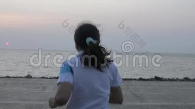 亚洲妇女慢<strong>跑到</strong>海岸后景，早上在普吉岛将手臂举<strong>到</strong>空中。