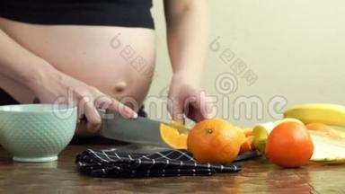 孕妇在厨房里做健康的零食，香蕉和橘子切片