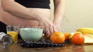 孕妇在厨房里做健康的零食，香蕉和橘子切片