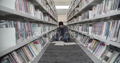大学生坐在图书馆的地板上，看书。 翻书页。 中弹