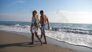 在度假胜地休息时，一对情侣<strong>牵着</strong>手在海岸散步。 男人和女人在海滩上漫步，享受
