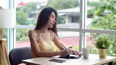 年轻漂亮的女人在咖啡店写预约书