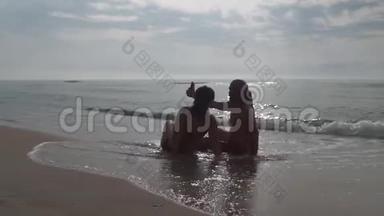 一对夫妇坐在海滩上，在<strong>日</strong>出时用智能<strong>手机</strong>拍照。 浪漫夫妇在夏天用智能<strong>手机</strong>拍照。