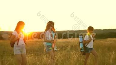 妈妈和她的女儿一起旅行。 母亲和孩子是游客。 女孩们在夕阳下穿越田野。 Hiker女孩