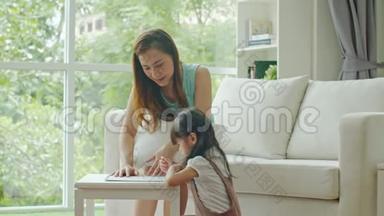 年轻的母亲教可爱的女儿画画