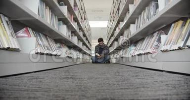 大学生坐在图书馆的地板上，看书。 垂直形状，中间视图