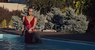 穿红色<strong>衣服</strong>的女人坐在池边，蘸着她的腿，4K