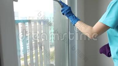 女人擦窗户。 一个匿名家庭主妇或清洁工用刮刀清洗窗户的库存视频。