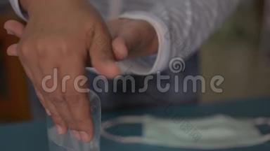 一名妇女在佩戴防护面罩前将洗手液滴入手中并对其进行消毒。