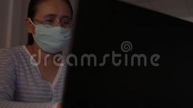 戴防护面罩的女人在办公桌上工作，家里有笔记本电脑。 冠状病毒保护。 COVID-19疫情。