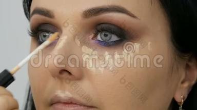 面部轮廓化妆师用刷子引导女人在脸上涂上粉末、粉底或遮瑕剂。 Lilac