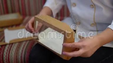 手是折叠纸盒.. 厨师正在他的膝盖上折叠一个礼品盒。