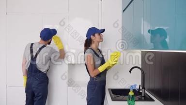 清洁公司漂亮的年轻工人戴着橡胶手套，在高科技厨房里扭动着