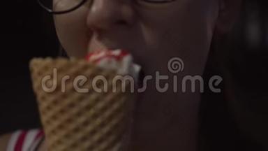 在黑暗中在户外吃<strong>冰淇淋</strong>的年轻女孩闭上嘴。 一个女孩吃甜点<strong>冰淇淋</strong>和<strong>草莓</strong>果酱。