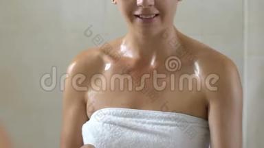 女人在浴室淋浴后在脸上涂<strong>润肤露</strong>，护肤