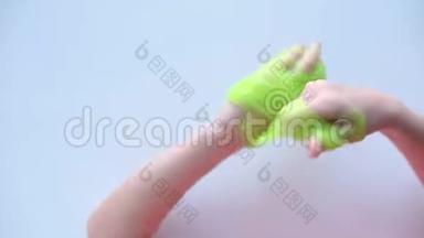 女孩向两边伸展绿色<strong>黏液</strong>。 孩子们的手在玩<strong>黏液</strong>玩具。 在白色上做<strong>黏液</strong>。 时髦的液体玩具棒