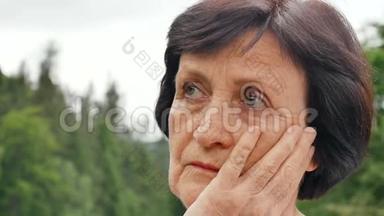 一位留着乌黑短发、<strong>满脸皱纹</strong>、想着退休后孤独生活的老年妇女的户外肖像画