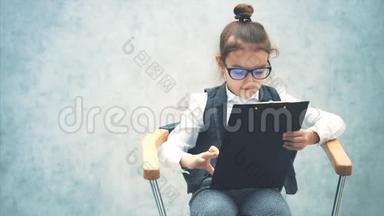 一个女老板坐在椅子上，拿着一个文件夹和一支铅笔。 灰色背景。 特写镜头。 写一支铅笔。
