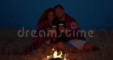 一对浪漫的情侣晚上<strong>围坐</strong>在篝火旁。